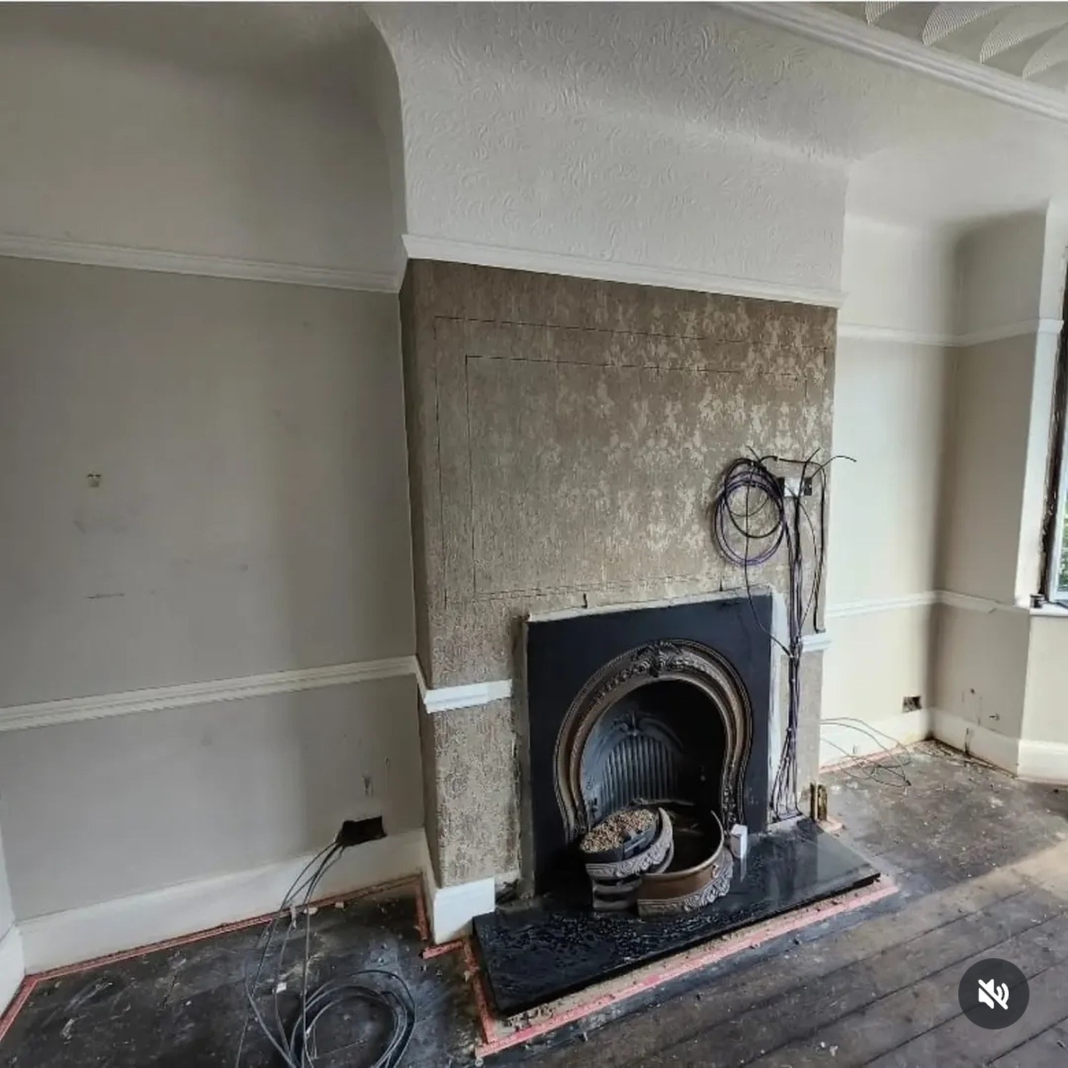 Before: original cast-iron fireplace, bare floorboards and exposed cables before the media wall build